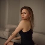 young woman in a black dress sitting on a sofa