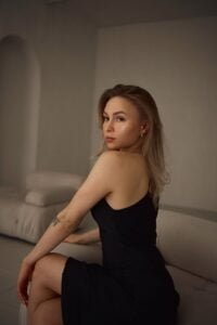 young woman in a black dress sitting on a sofa
