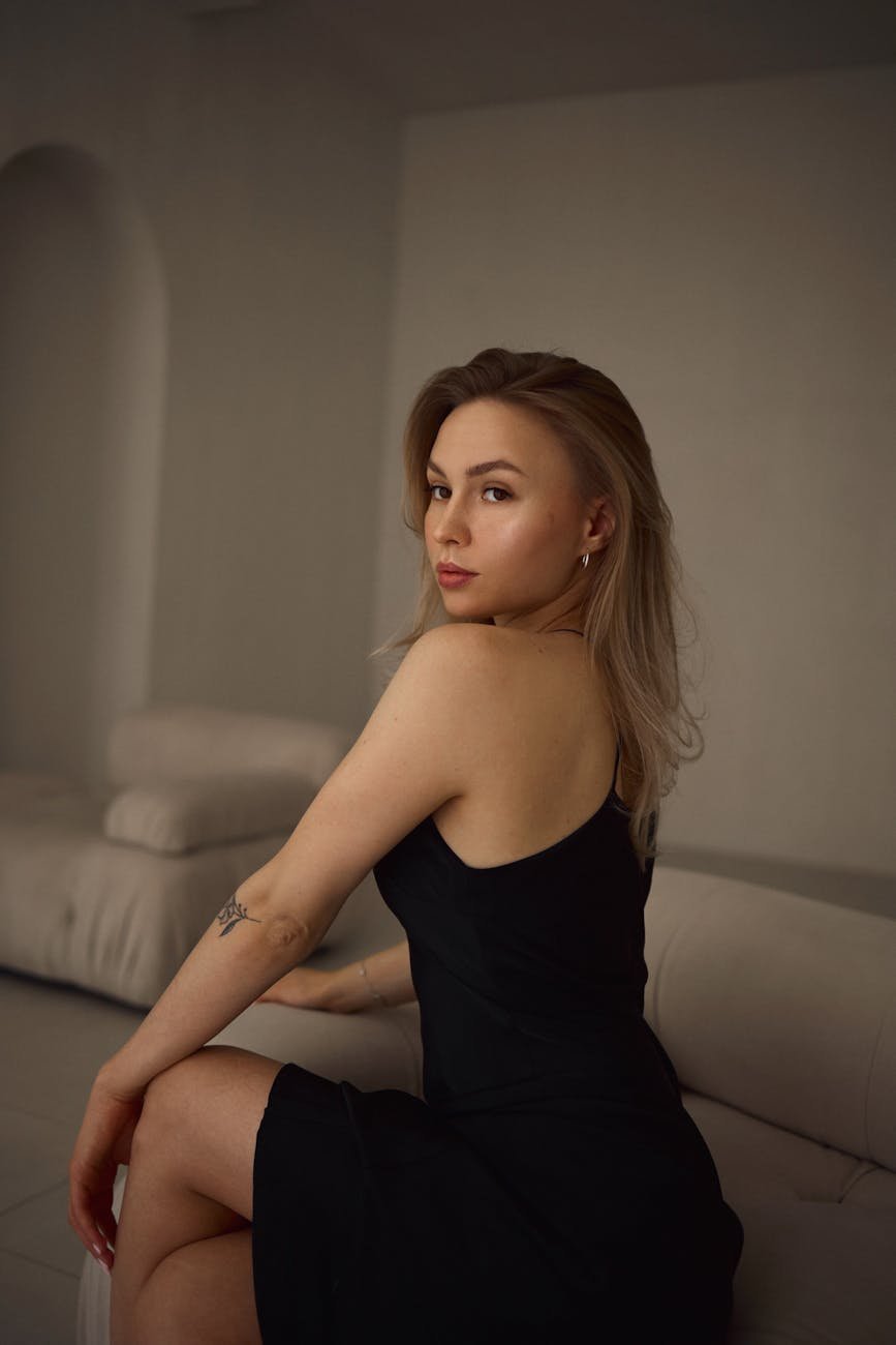 young woman in a black dress sitting on a sofa