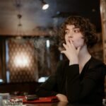 woman in black long sleeve smoking cigarette