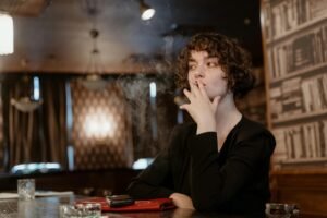 woman in black long sleeve smoking cigarette