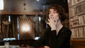 woman in black long sleeve smoking cigarette