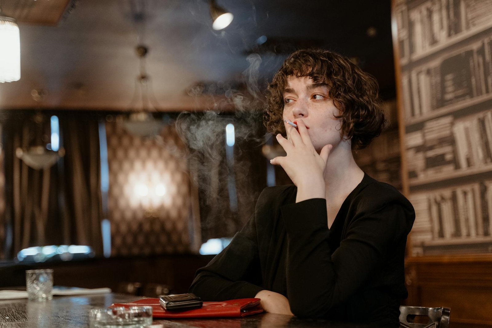 woman in black long sleeve smoking cigarette